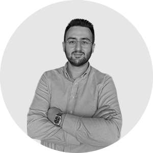 Gözlüklü Yunus Yılmaz'ın kolları çapraz siyah-beyaz dairesel portresi.